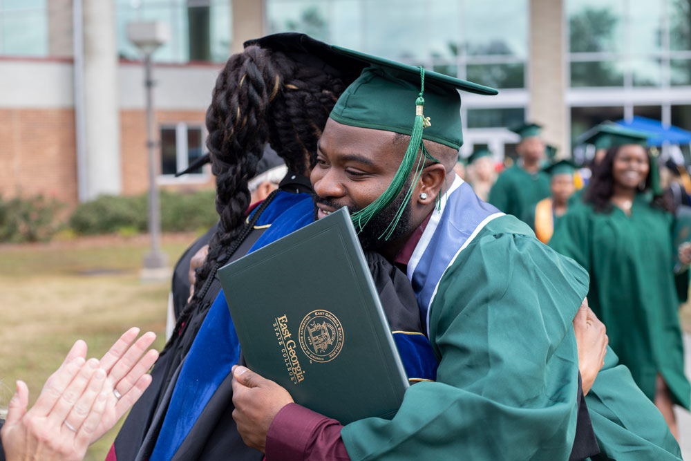 student hugging professor at graduation